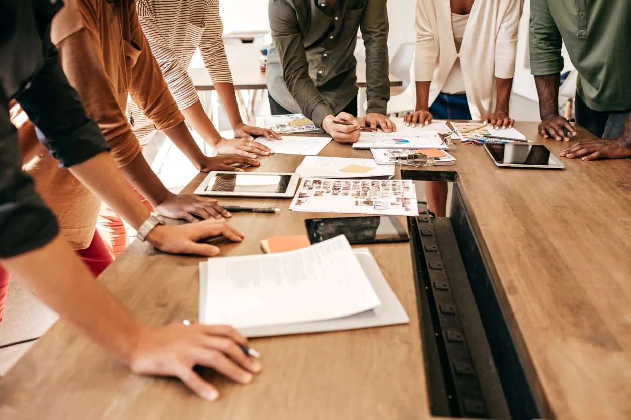 Une équipe penchée sur des documents de travail autour d'une table